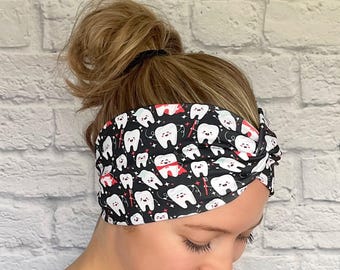 May include: A black headband with a white tooth pattern. The teeth are smiling and have red accents. There is a toothbrush and floss on the headband.