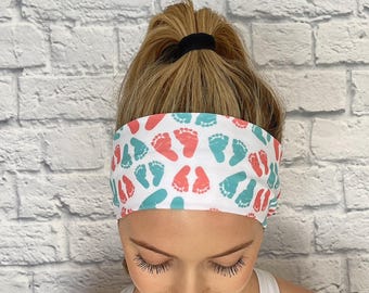 May include: White headband with a repeating pattern of pink and teal baby footprints.
