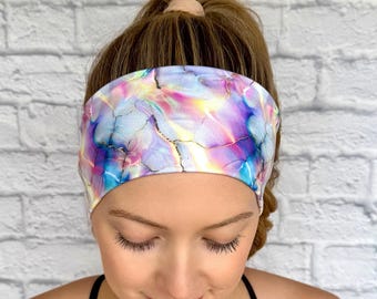 May include: A headband with a colorful marble pattern in shades of pink, blue, purple, and yellow. The headband is made of a soft, stretchy fabric and is perfect for keeping hair out of your face.