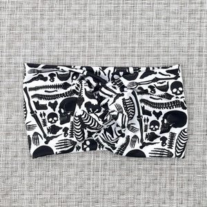 White, wide twist headband with black skeleton print.