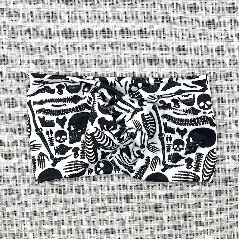 White, wide twist headband with black skeleton print.