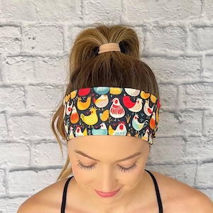 Woman with hair in curled ponytail wearing navy blue headband with chicken print.