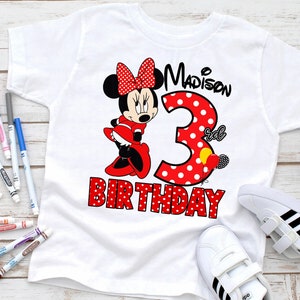 May include: White t-shirt featuring a red and white polka dot Minnie Mouse design. The shirt reads "Madison's 3rd Birthday".