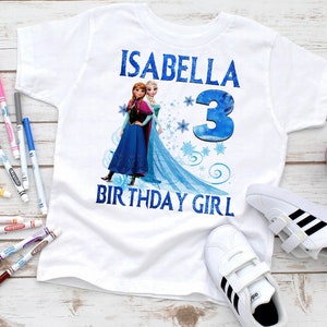 Puede incluir: Camiseta blanca con una imagen azul y blanca de Elsa y Anna de Frozen. La camiseta dice "Isabella 3 Birthday Girl".