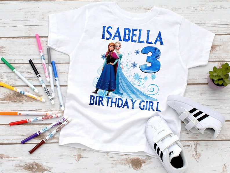 Puede incluir: Camiseta blanca con una imagen azul y blanca de Elsa y Anna de Frozen. La camiseta dice "Isabella 3 Birthday Girl".