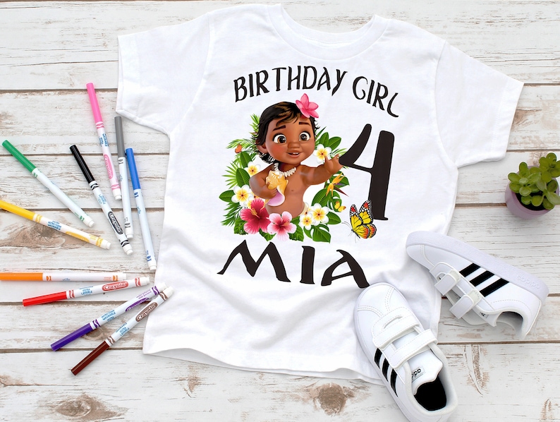 Pode incluir: Camiseta branca com um gr&aacute;fico colorido de um personagem de desenho animado, flores e borboletas. O texto "Birthday Girl 4 Mia" est&aacute; impresso na camiseta.