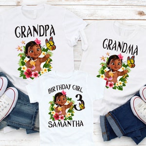 Pode incluir: Tr&ecirc;s camisetas brancas com uma imagem de desenho animado de uma menina polin&eacute;sia beb&ecirc; usando um colar de flores e segurando uma flor. As camisetas dizem "Grandpa", "Grandma" e "Birthday Girl 3 Samantha".