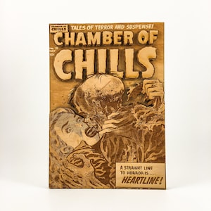 May include: A wood-carved replica of a vintage horror comic book cover. The cover features a zombie-like creature biting a woman's neck. The title of the comic is "Chamber of Chills" and the tagline is "A straight line to horror is... Heartline!"