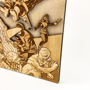 May include: A wooden wall art piece featuring a comic book style illustration of superheroes fighting a monster. The artwork is laser cut and has a brown wood finish.