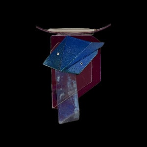 Może przedstawiać: Geometriczna abstrakcyjna rzeźba ścienna wykonana z warstwowego szkła w odcieniach niebieskiego i fioletowego.