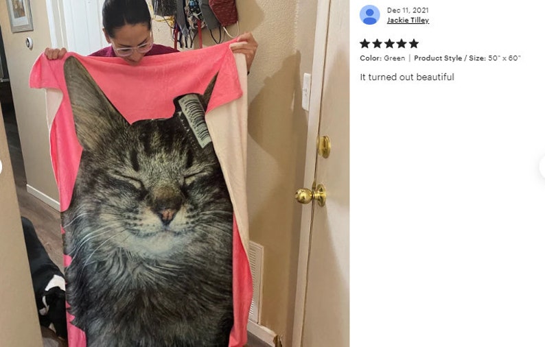 May include: A large, rectangular green and pink blanket featuring a close-up image of a cat's face. The blanket measures 50 x 60 inches. The cat has closed eyes and a serene expression.