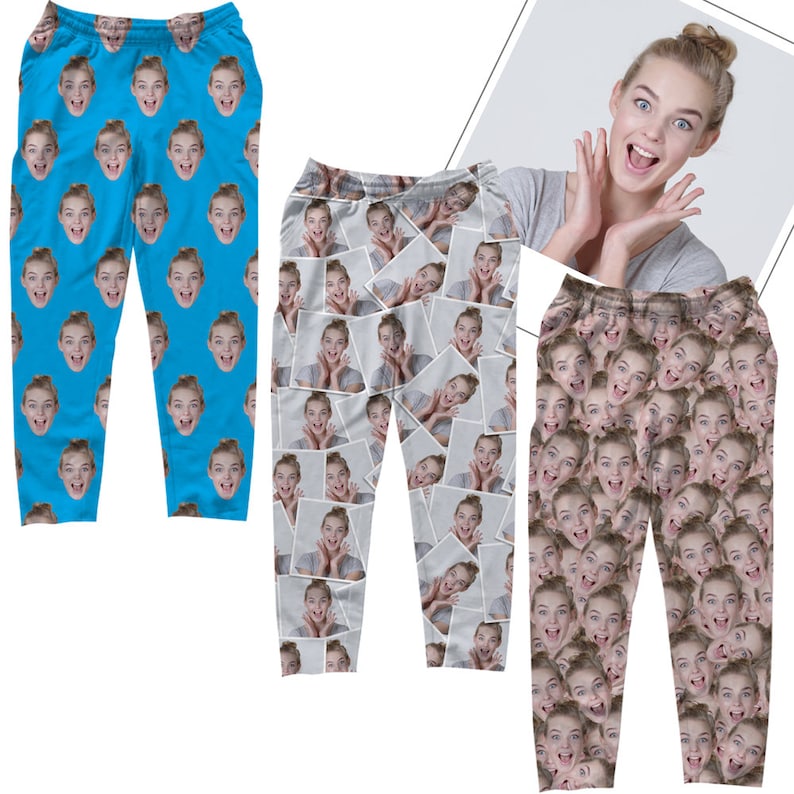 Op de afbeelding: Drie paar bedrukte broeken met een herhalend patroon van een vrouwen gezicht. De broeken zijn in drie verschillende kleuren: blauw, grijs en bruin. De vrouw op de foto glimlacht en heeft haar haar naar achteren gebonden.