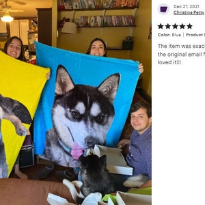May include: Three people hold up large, personalized dog blankets. One is yellow, and the other is blue, each featuring a close-up of a dog's face. The blankets measure 50 x 60 inches.