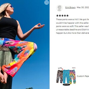 Op de afbeelding: Een vrouw draagt een kleurrijke bedrukte broek met gezichten erop. De broek is zacht en comfortabel. De vrouw zit op een houten paal met haar armen uitgestrekt in een yogapose. De achtergrond is een blauwe lucht.