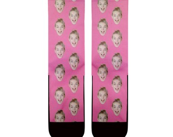 May include: A pair of pink socks with a repeated pattern of a woman's face. The socks have black toes and heels.