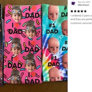 Pu&ograve; includere: Tre paia di calzini con design unici. Un paio presenta facce di gatto e la scritta "BEST DAD EVER". Un altro paio ha uno sfondo rosa con "I ❤️ DAD" e facce di bambino. Il terzo paio ha uno sfondo tie-dye con "#1 DAD" e facce di bambino.