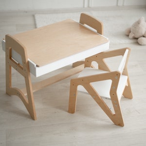 May include: A wooden children's table and chair set with a white top and drawer. The table has a curved design and the chair has a triangular shape.