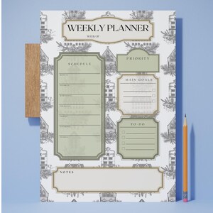 Peut inclure: Planificateur hebdomadaire avec un motif décoratif et des accents verts et dorés. Le planificateur comprend des sections pour l'emploi du temps, les priorités, les principaux objectifs, les tâches à faire et les notes. Un clip en bois et un crayon sont également visibles.