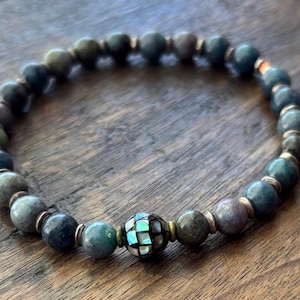 May include: A blue and green gemstone bracelet with a silver and abalone shell bead in the center.