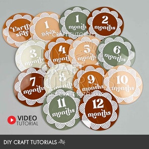May include: A set of 12 round, colorful baby milestone stickers with white scalloped edges and white text. The stickers feature the words "Earth side", "1 week", "1 month", "2 months", "3 months", "4 months", "5 months", "6 months", "7 months", "8 months", "9 months", "10 months", "11 months", and "12 months".