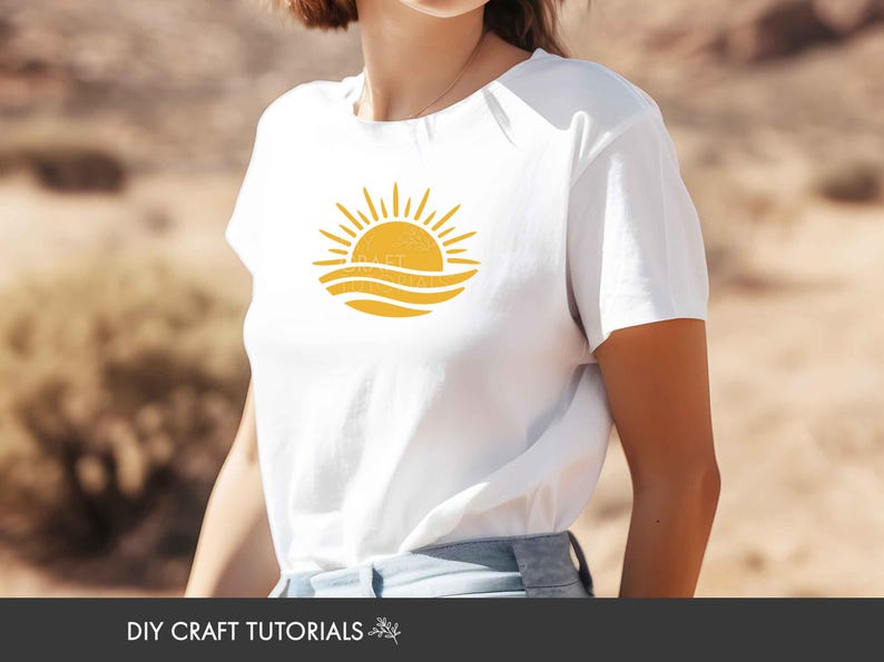 May include: A white short-sleeved t-shirt featuring a yellow graphic print on the chest. The graphic depicts a stylized sun rising above wavy lines. The shirt is worn with light blue denim bottoms.