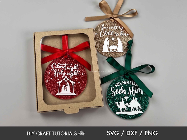 May include: Three round Christmas ornaments with glitter and white text. The ornaments are red, gold, and green. The red ornament says "Silent night Holy night" and features a nativity scene. The gold ornament says "for unto us a Child is born" and also features a nativity scene. The green ornament says "Wise men still Seek Him" and features three wise men riding camels.