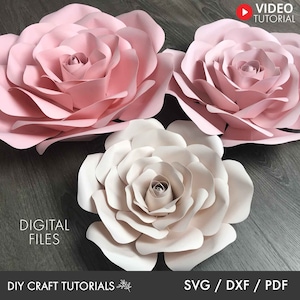 May include: Three large paper flowers, two pink and one white, with layered petals. The flowers are arranged on a woodgrain surface. The text "DIGITAL FILES" and "SVG / DXF / PDF" are visible at the bottom of the image.