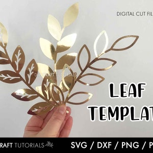 Puede incluir: Plantilla de hoja de oro archivos de corte digital para manualidades. La imagen muestra una mano sosteniendo un diseño de hoja de oro recortada de papel. El texto "LEAF TEMPLATE" es visible en la imagen.