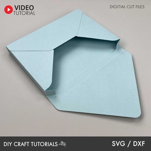 May include: A light blue paper envelope with a fold-over flap. The envelope is open and the inside is visible. The text "DIGITAL CUT FILES" is at the top of the image. The text "DIY CRAFT TUTORIALS" is at the bottom of the image. The text "SVG / DXF" is at the bottom right of the image.