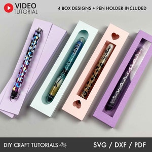 May include: Four different pen holder box designs with a window to display the pen. The boxes are in purple, pink, blue, and light purple. The text "4 BOX DESIGNS + PEN HOLDER INCLUDED" is at the top of the image. The text "DIY CRAFT TUTORIALS" is at the bottom left of the image. The text "SVG / DXF / PDF" is at the bottom right of the image.