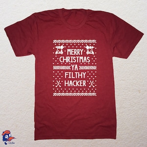 May include: Red t-shirt with a white Christmas sweater design featuring golf carts and the text "Merry Christmas Ya Filthy Hacker".
