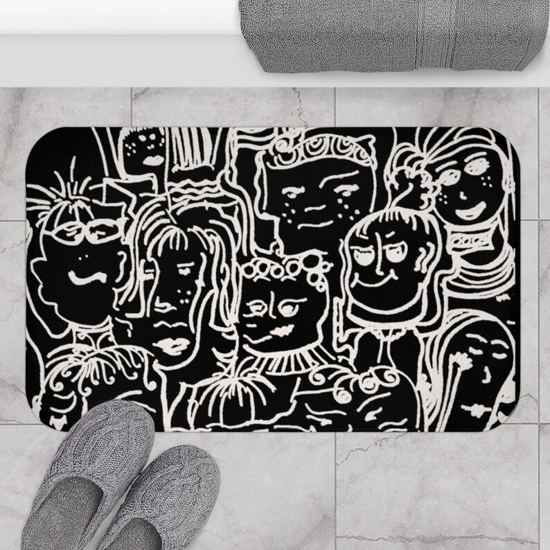 May include: Black and white bath mat with a graphic design of multiple faces. The faces are drawn in a simple, cartoon style.