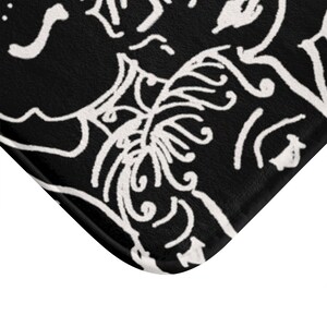May include: Black and white bath mat with a decorative design of swirling lines and shapes.