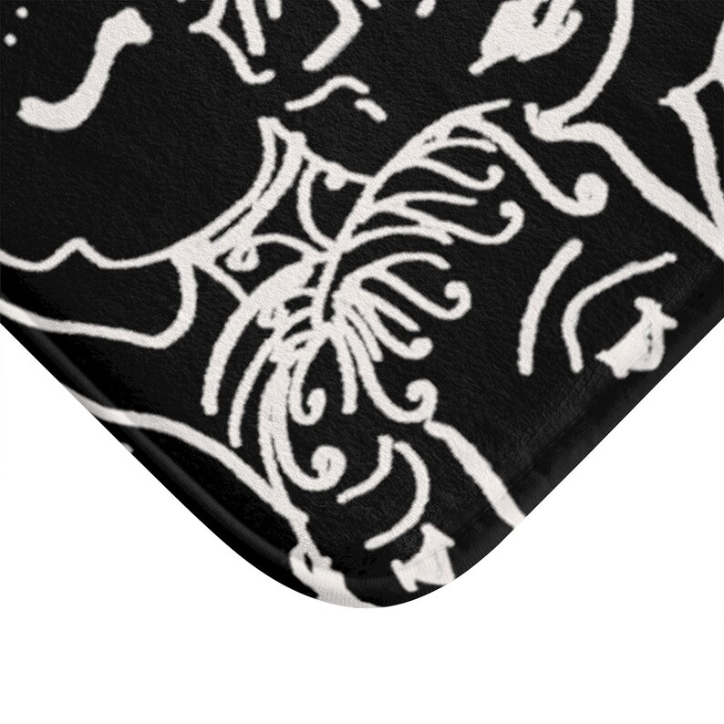 May include: Black and white bath mat with a decorative design of swirling lines and shapes.