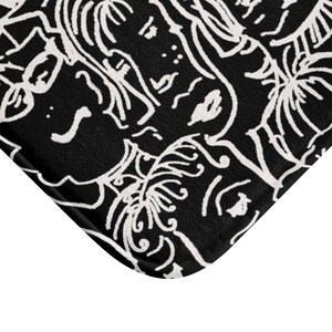 May include: Black and white bath mat with a repeating pattern of stylized faces and leaves.