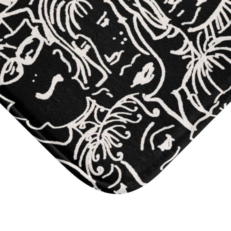 May include: Black and white bath mat with a repeating pattern of stylized faces and leaves.