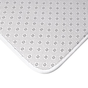 May include: Close-up of the white underside of a bath mat. The mat has a white border and a black, repeating pattern of small dots.