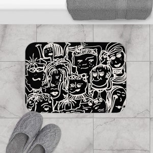 May include: Black and white bath mat with a graphic design of many faces. The faces are drawn in a cartoon style and are all different shapes and sizes.