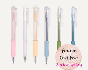 Puede incluir: Siete cuchillos de precisión para manualidades con barriles de plástico transparente y tapas de colores. Los colores son rosa, gris claro, amarillo claro, azul claro, verde, azul oscuro y verde claro. El texto de la imagen dice "Cuchillo de precisión para manualidades 7 opciones de color".