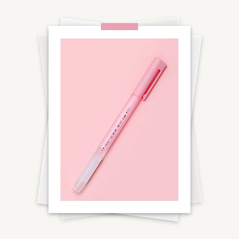 May include: A pink pen with a matching cap and clip, set against a pink background. The pen has text printed on the side. The pen is on a white background.