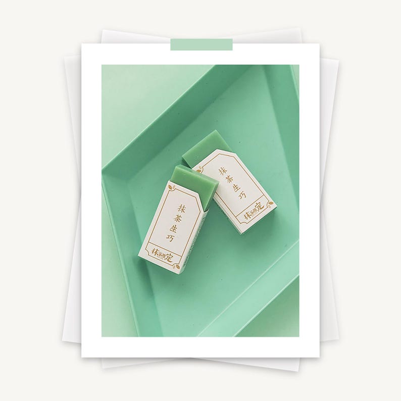 May include: Two green bars of soap with white labels that say "抹茶 生 巧" and "抹茶 生 巧" in Japanese. The soap is sitting on a light green tray.