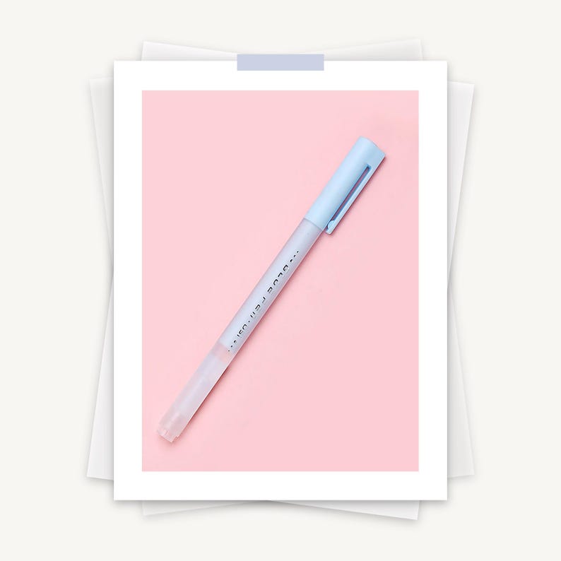 May include: A light blue pen with a matching cap and clip, set against a pink background. The pen's barrel is transparent, and the text "...BLUE PEN..." is printed on the side. The pen is resting on a white paper.