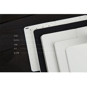 May include: Five different notebooks stacked on top of each other. The notebooks are all white with different patterns. The patterns are: daily, black, grid, dot, and blank.