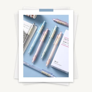 K&ouml;nnte beinhalten: F&uuml;nf durchsichtige mechanische Bleistifte mit verschiedenen Farben: blau, rosa und hellblau. Die Stifte haben einen Durchmesser von 0,5 mm und einen transparenten Radiergummi am Ende. Die Stifte sind in einer Reihe auf einer hellblauen Oberfl&auml;che angeordnet. Der Text auf der Schachtel lautet "DM-70 シャープ 0.5 mm / 12" und "DOMI STATIONERY".