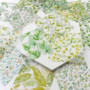 May include: A collection of botanical-themed paper sheets showcasing diverse green leaf and floral patterns. Designs include tropical leaves, delicate vines, and scattered blossoms, all against a white backdrop. The sheets are arranged on a white surface.