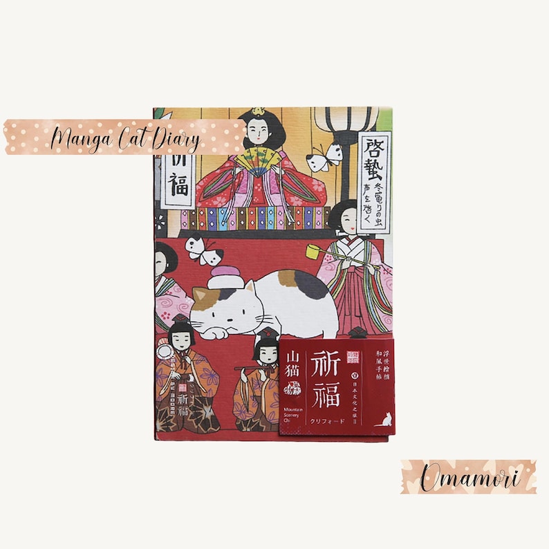 May include: A red and gold Japanese-style diary with a cat illustration and the text "Manga Cat Diary" and "啓蟄" on the cover. The diary is accompanied by a small red and gold charm with the text "祈福" and "山猫" on it.