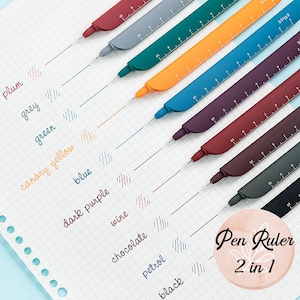 Puede incluir: Un conjunto de diez bolígrafos coloridos con reglas incorporadas. Los bolígrafos están dispuestos en una fila de arriba a abajo, con los colores ciruela, gris, verde, amarillo canario, azul, morado oscuro, vino, chocolate, petróleo y negro. Los bolígrafos tienen una regla en un lado y un bolígrafo en el otro. El texto "Pen Ruler 2 in 1" es visible en la esquina inferior derecha de la imagen.