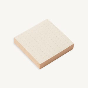 May include: A stack of white sticky notes with a subtle dotted pattern. The notes are square shaped and have a slightly textured surface.
