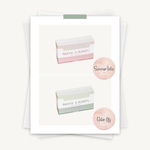 May include: Two boxes of blank note cards with the text "Note Cards" on the front. The top box is pink and the bottom box is green. The boxes are on a white background. The image also includes two pink circles with floral designs and the text "Summer Isles" and "Water Lily" in black.