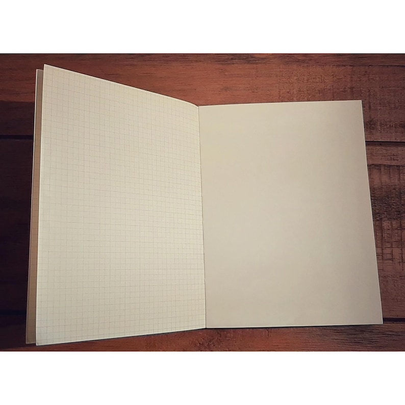May include: An open notebook with a grid pattern on the left page and a blank page on the right. The notebook has a brown cover.
